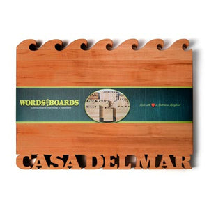 cherry wood cutting board with waves on top, words cut out of bottom