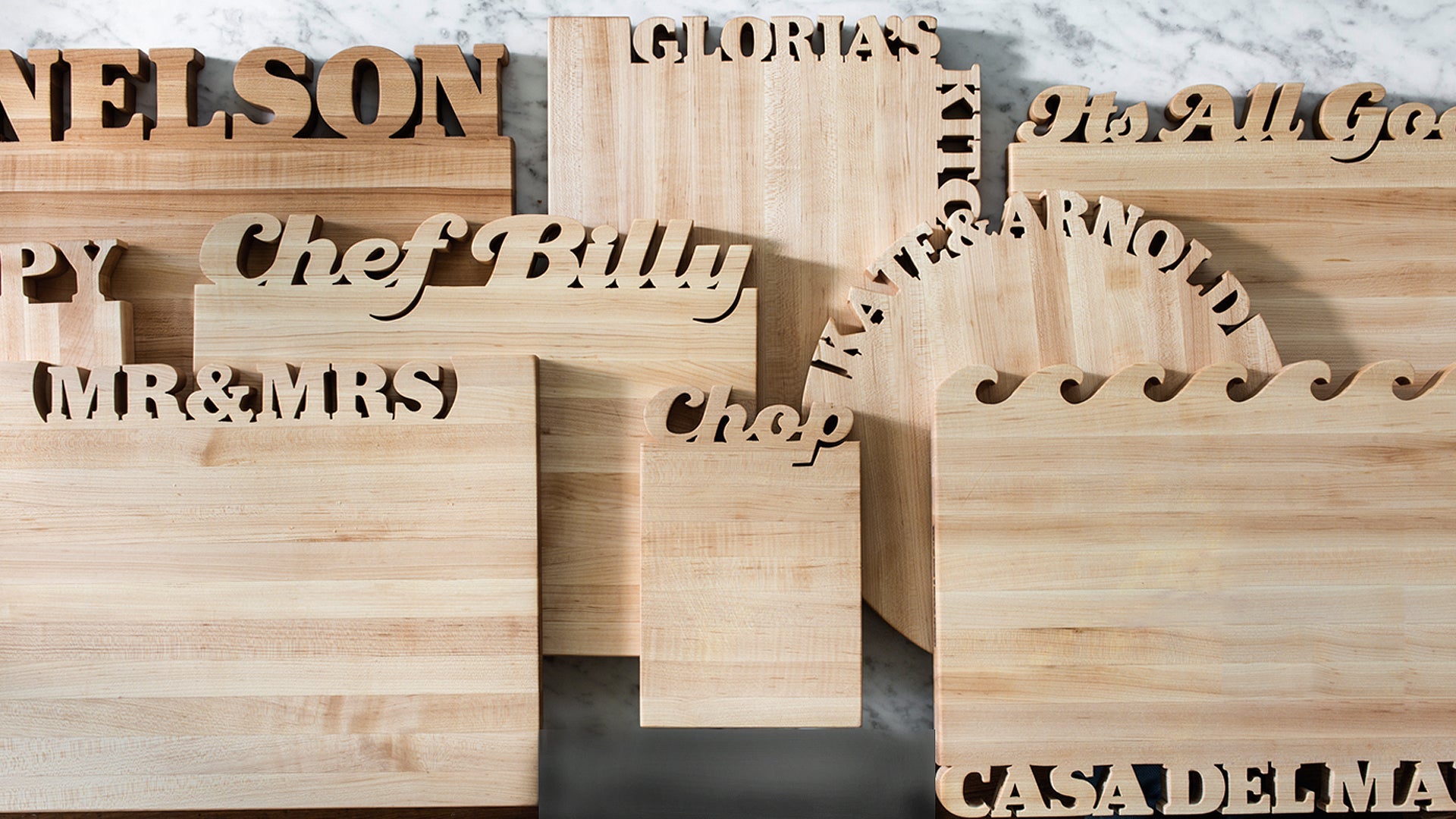 A stack of various size and shape cutting boards standing against marble background