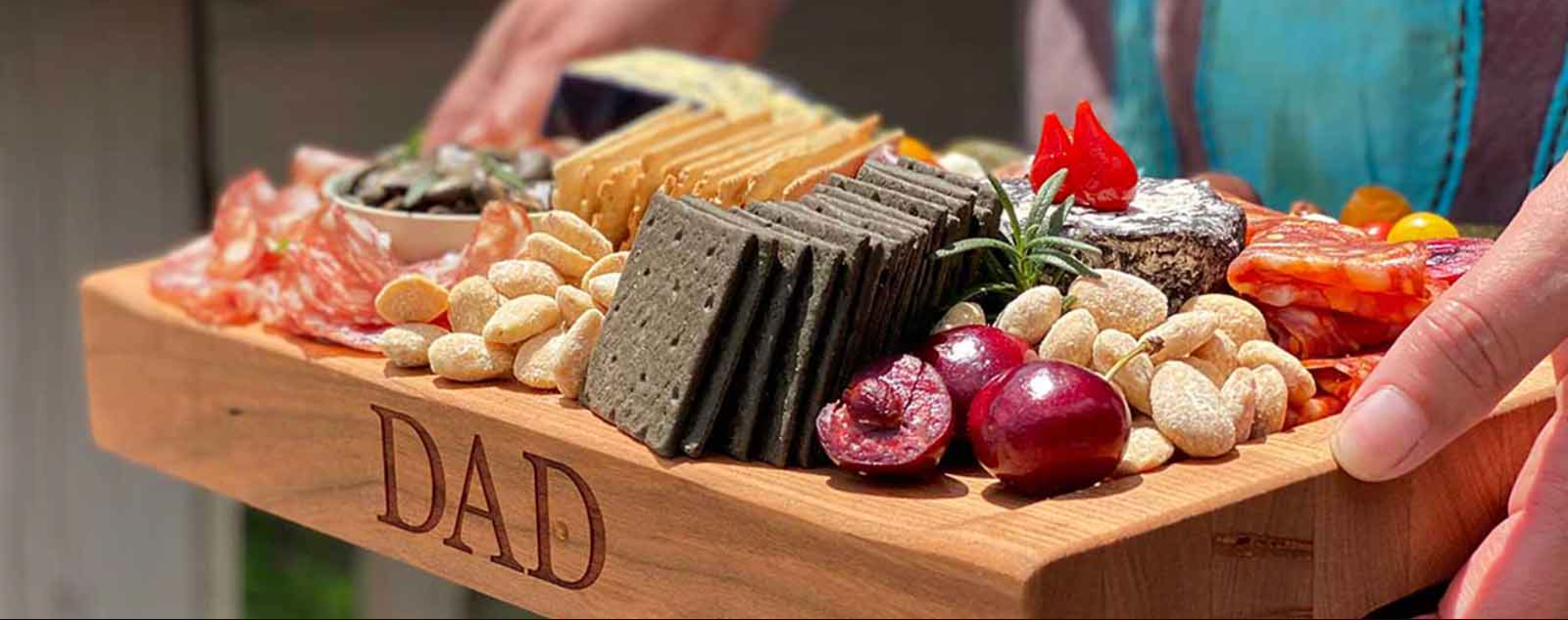 small sloped board with cheese and crackers spread, person holding board