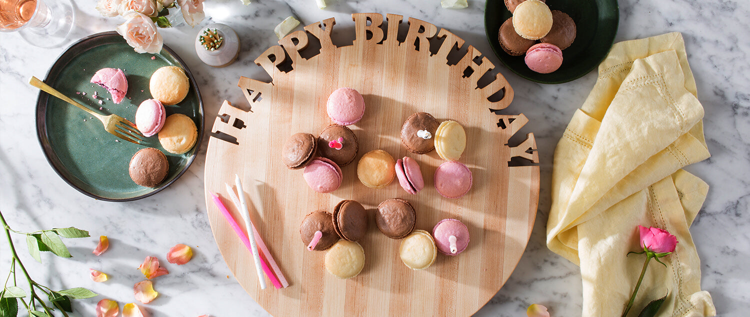 Round cutting board, Happy birthday cut out of the wood, macaroons on the board, marble background