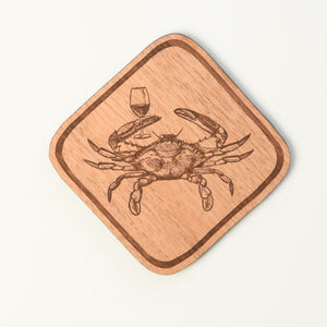 Wooden coaster with a crab and wine glass design on a white background