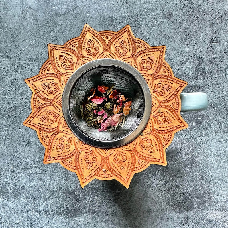 Decorative tea infuser with mandala design on a gray background