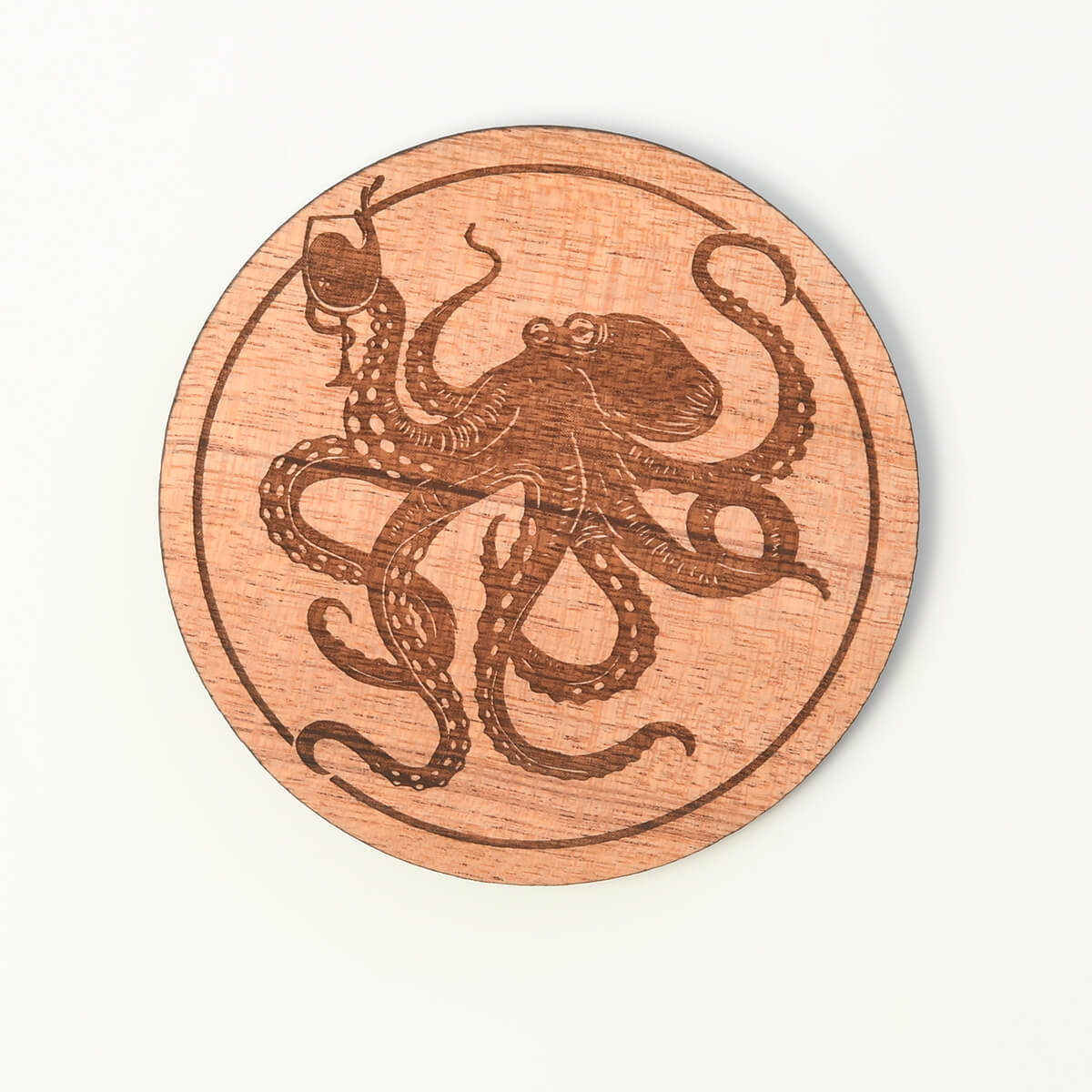 Wooden coaster with an engraved octopus design on a white background