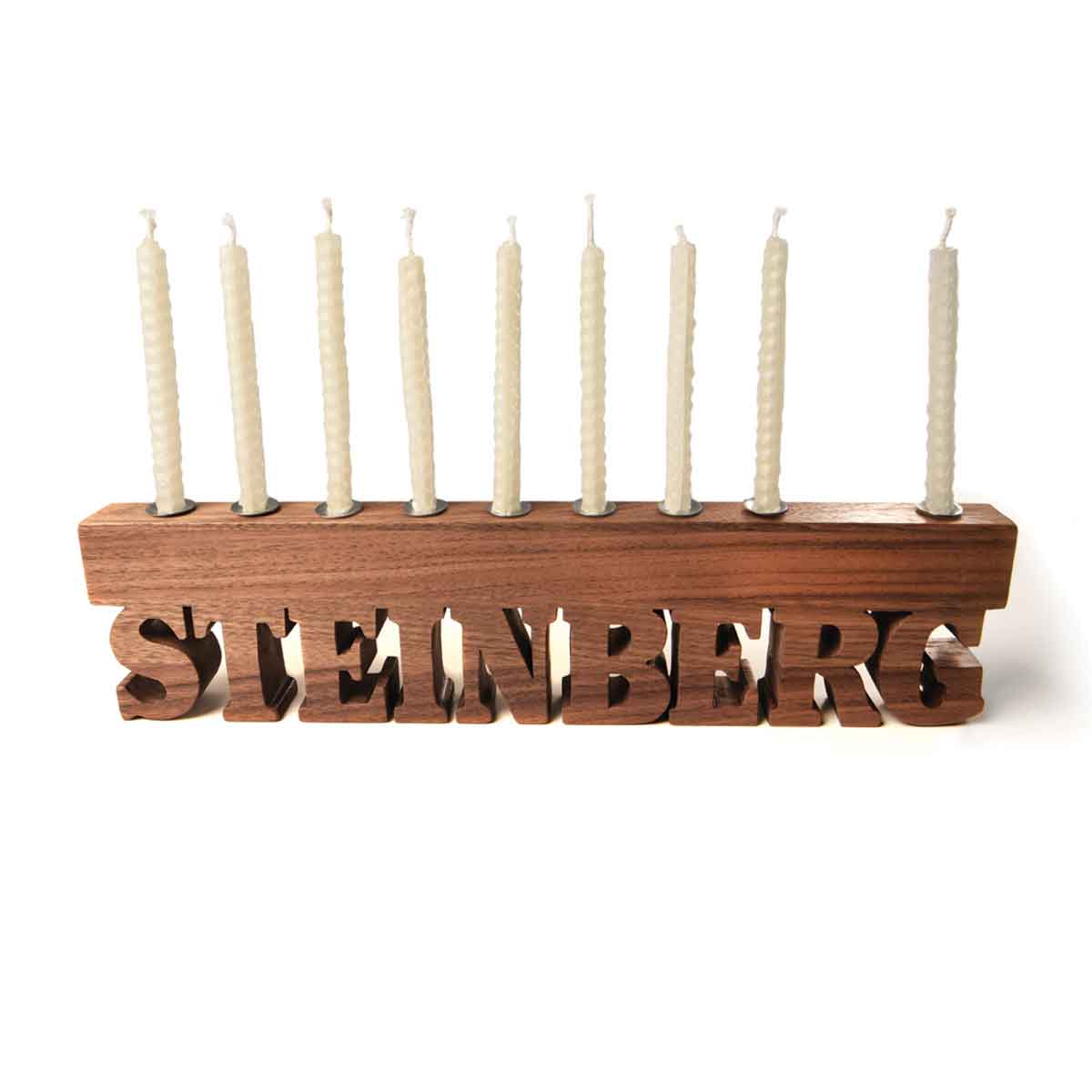 Wooden menorah with 'Steinberg' engraving and unlit candles on a white background