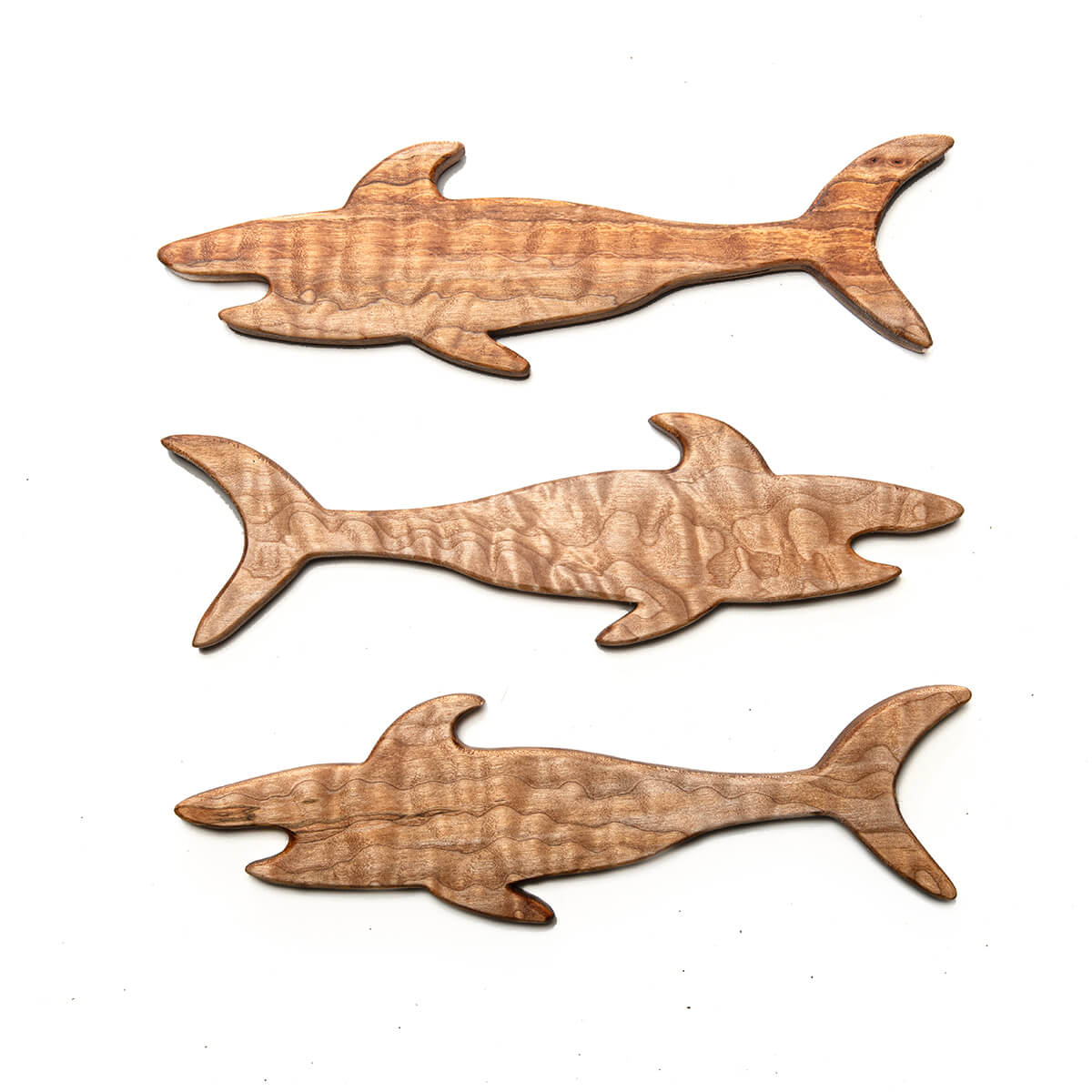 Three wooden shark-shaped push pull sticks on a white background