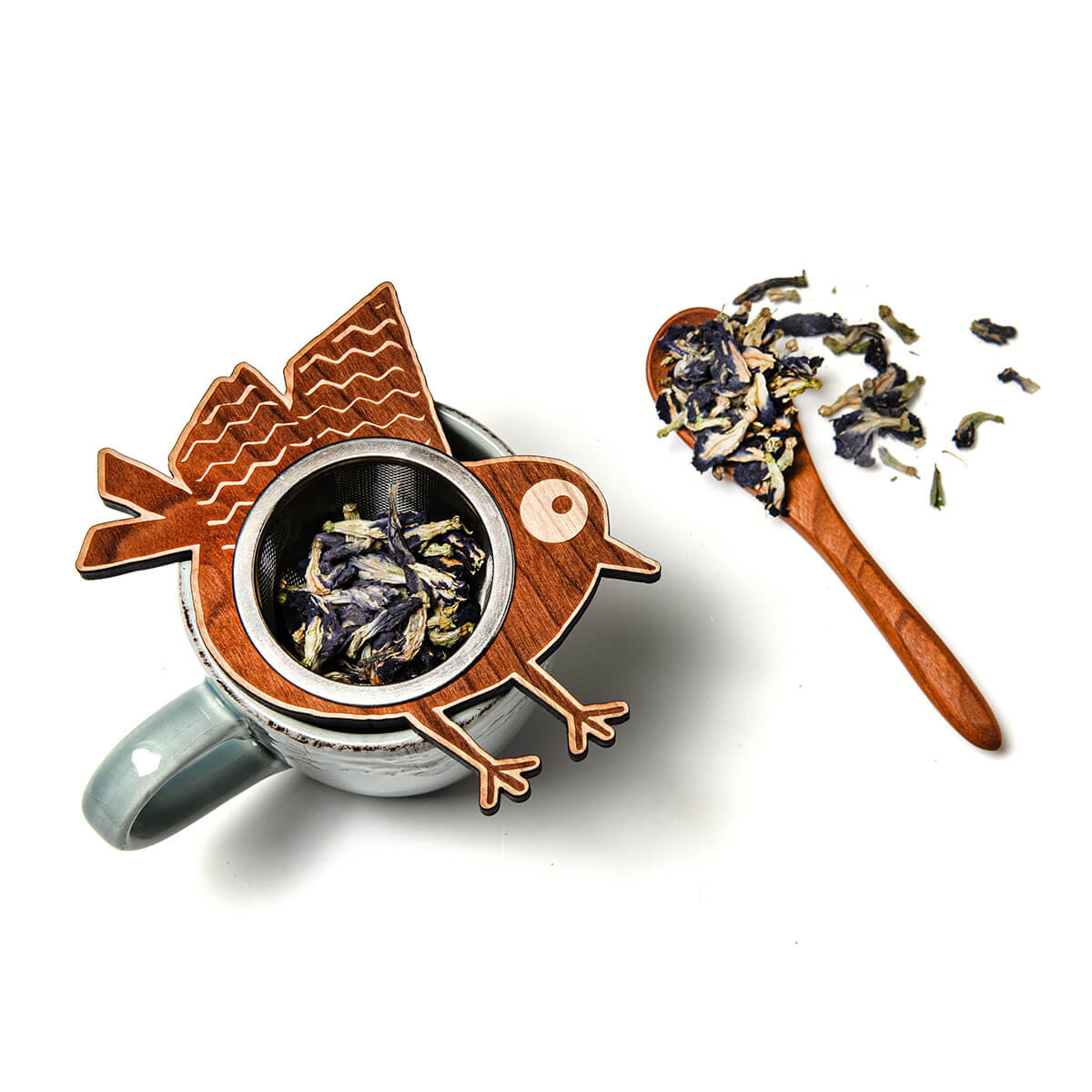 Bird-shaped wooden tea infuser with a spoonful of tea leaves on a white background