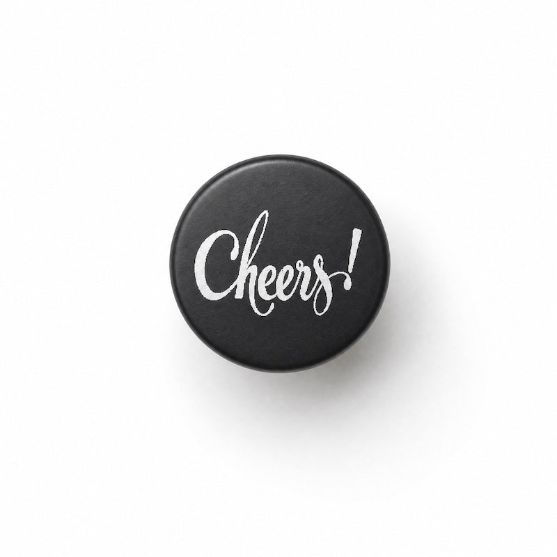 black metal bottle stopper with Cheers! engraved on top, white background