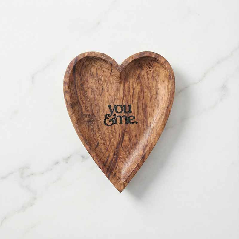 Wooden heart-shaped trinket dish with 'you & me' engraving on a marble surface