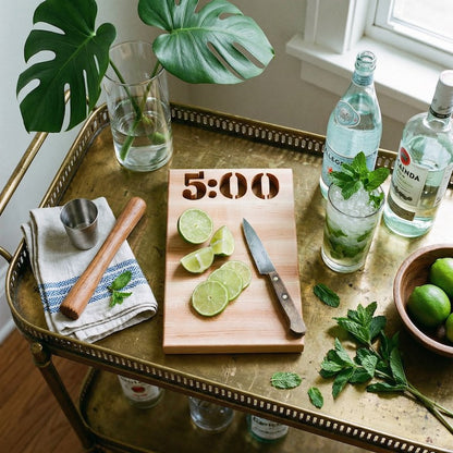 Bar cart with lime slices, cutting board, and drinks on a wooden surface.