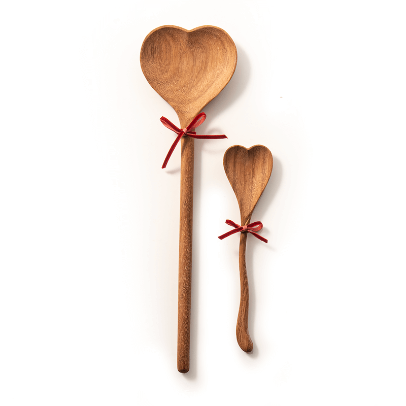 2 wood heart spoons each with small red bow on white background