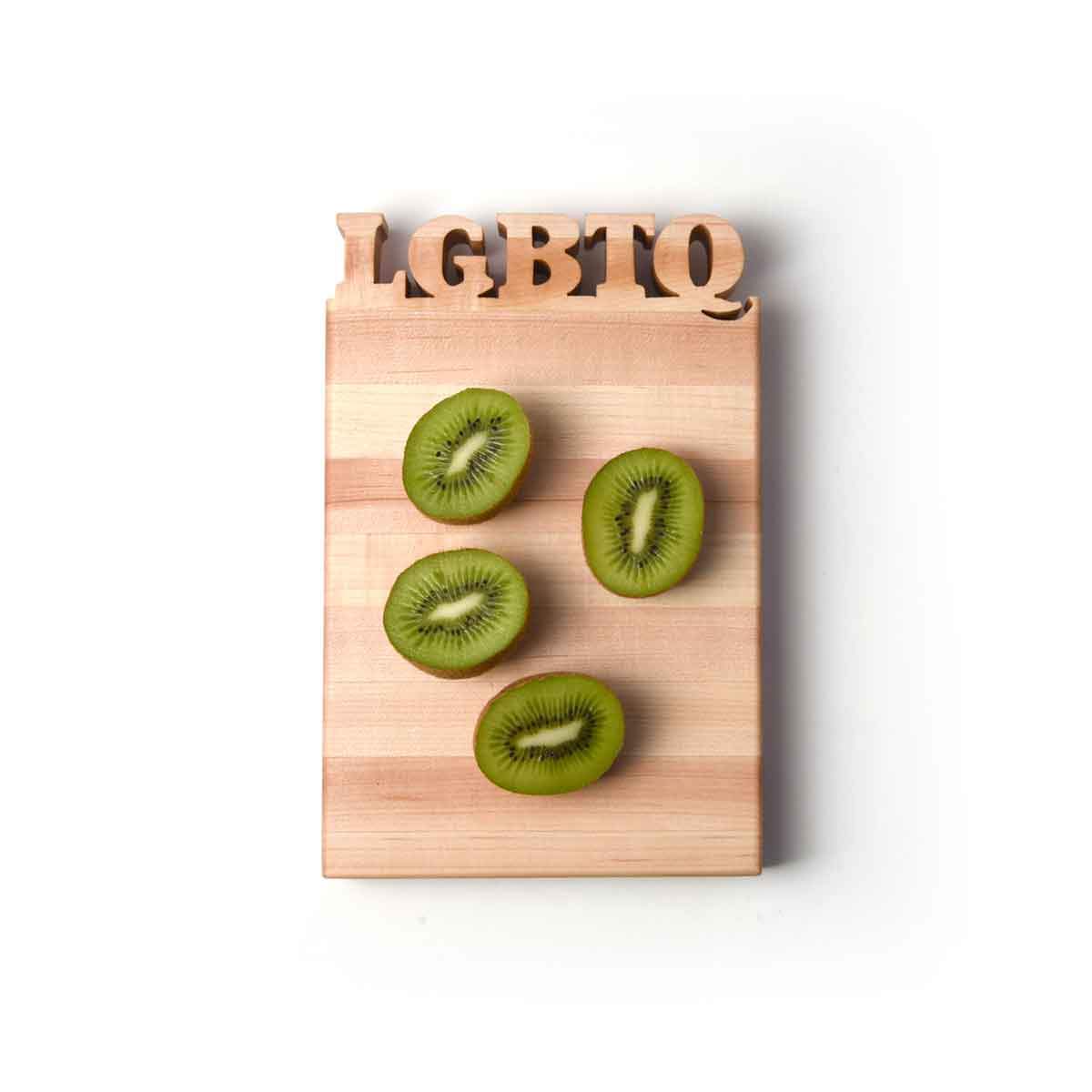 LGBTQ letters cut out of wooden cutting board