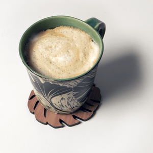 Monstera leaf shaped coaster with coffee mug on top