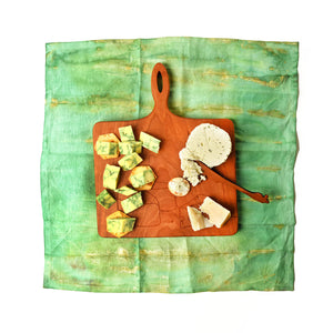 Cherry wood cheese board, on green linen napkin 